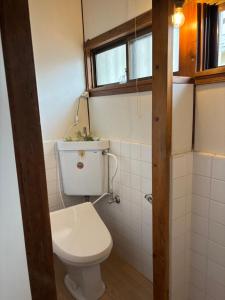 a small bathroom with a toilet and a window at Vineyard Vista ENZAN in Koshu
