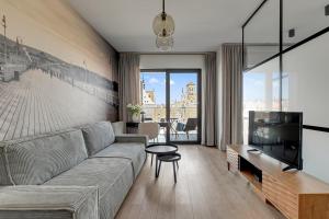 a living room with a couch and a flat screen tv at DEO PLAZA Apartments & Riverside by Downtown Apartments in Gdańsk +44 photos
