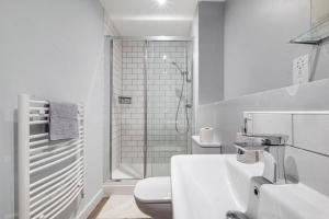 a white bathroom with a shower and a toilet at Charming Deritend Apartment with Full Access for Wheelchairs in Birmingham