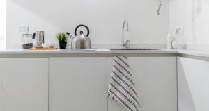 une cuisine avec des armoires blanches et un évier dans l'établissement JOIVY Elegant Studio in the Centre of Milan, à Milan