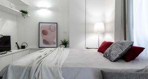 - une chambre blanche avec un grand lit et des oreillers rouges dans l'établissement JOIVY Elegant Studio in the Centre of Milan, à Milan 4 autres photos
