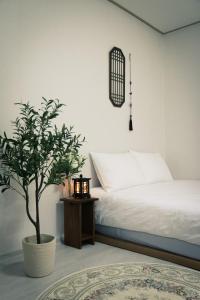 a bedroom with a white bed and a potted tree at Bitdamjip Near Hwaseong Fortress and Suwon Station in Suwon