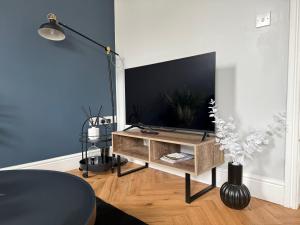 a living room with a flat screen tv on a table at Modern 1 & 2 Bedroom Apartments near Queens University Belfast by MonoStays in Belfast