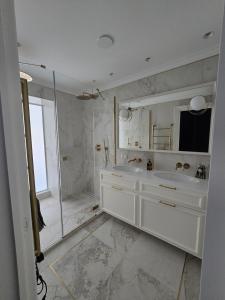 a white bathroom with a shower and two sinks at Vilnius Central House in Vilnius