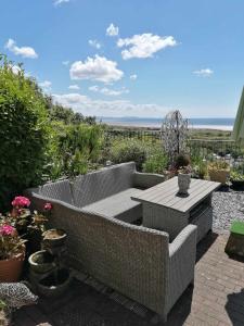 Un patio con mesa y sillas y flores. en Bay View, en Pendine