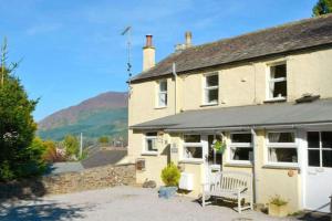 a house with a bench in front of it at Cottage - Sleeps 4 - Pets Ok - Garden - Parking in Keswick
