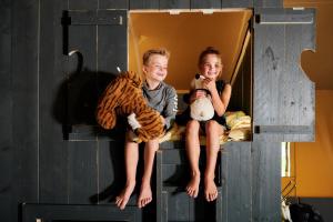 a boy and a girl sitting on a bunk bed at Glamping bij Vakantiepark De Sallandshoeve in Nieuw-Heeten +2 photos