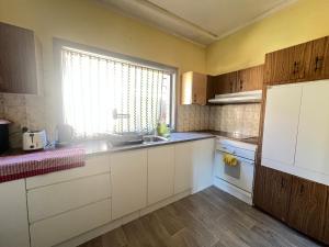 a kitchen with white cabinets and a sink and a window at Cozy Queen Room Next to Station and Shops - PH6 in Pendle Hills