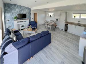 Una sala de estar con un sofá azul y una cocina. en Hoburne, en Bodmin