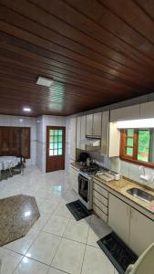 a large kitchen with white cabinets and a wooden ceiling at Sítio meu recanto in Paulo Lopes
