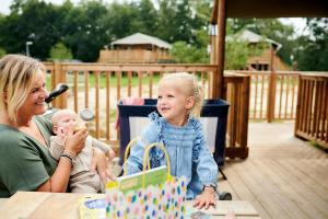 a woman and a little girl sitting at a table with a baby at Glamping bij Vakantiepark De Sallandshoeve in Nieuw-Heeten