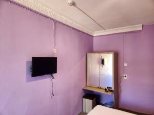a purple wall with a tv and a mirror at Çeşme MASAL in Çeşme