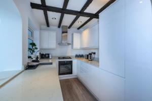 a kitchen with white cabinets and a wooden ceiling at Windsor Reach in Datchet