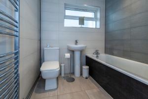 a bathroom with a toilet and a sink and a tub at Windsor Reach in Datchet +6 photos