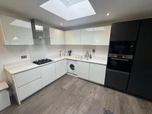 a kitchen with white cabinets and a washer at 2BR Flat in Prime Location in Hedgerley
