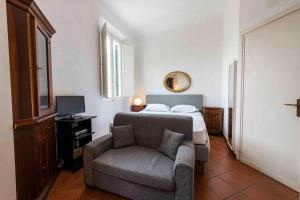 a bedroom with a bed and a couch and a television at Borgo Allegri Palace By MMega in Florence