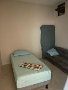 una piccola stanza con un letto e un lenzuolo verde di Quartos Privativos Stella Maris a Salvador