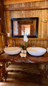 two sinks in a wooden bathroom with a mirror at Casa Eliza Trancoso, casa de luxo com vista mar in Trancoso