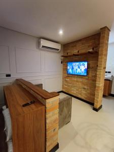 サン・ミゲウ・アルカンジョにあるApart Hotel da Serraのレンガの壁にテレビ付きのリビングルーム