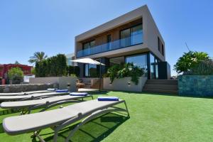 a row of lounge chairs in front of a house at La Atalaya del Salobre Golf in San Bartolomé
