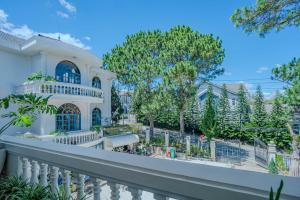 ein weißes Haus mit weißem Zaun und Bäumen in der Unterkunft Chu Mansion - Chill & Grill and Pickeball in Da Thien