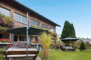 SibratsgfällにあるHaus Vögelの傘とベンチとテーブルのある建物