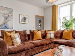 a living room with a brown couch with yellow pillows at Formans Lodge in Musselburgh