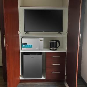 a kitchen with a microwave and a tv on a shelf at Hippo Zwartkop Suites in Centurion