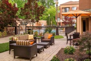 a patio with couches and chairs and an umbrella at Sonesta Select Durham Research Triangle Park in Durham