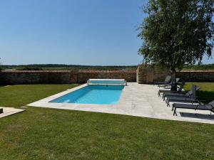 Saint-Hilaire-de-TalmontにあるVilla luxueuse rénovée à la Guittièreの椅子と木のある庭のスイミングプール