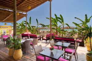 a restaurant with pink chairs and tables on a deck at Royal Nozha in Hammamet