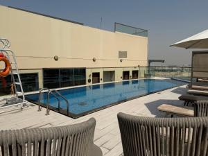 a swimming pool with two chairs and a building at Pavilion Hotel Al Jaddaf in Dubai