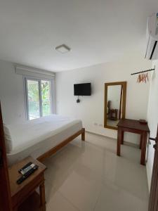 um quarto com uma cama, um espelho e uma mesa em Casa com varanda, ar condicionado pet friendly em Ilhabela