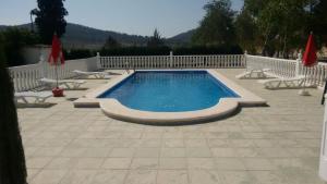 a swimming pool with chairs and a white fence at Casa Rural El Milano in Bullas