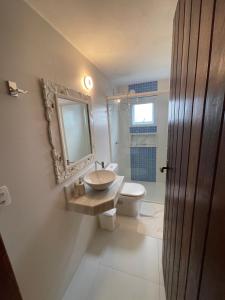 um banheiro com uma pia, um vaso sanitário e um espelho em Casa com varanda, ar condicionado pet friendly em Ilhabela