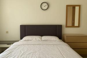 a bedroom with a bed and a clock on the wall at Cozy Studio Bintaro Icon Emerald by alonelyroom in Pondokaren