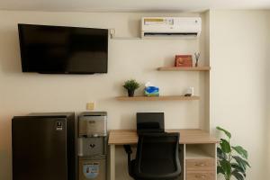 a room with a desk and a television on a wall at Cozy Studio Bintaro Icon Emerald by alonelyroom in Pondokaren +1 photo