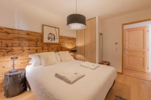 1 dormitorio con 1 cama blanca grande y pared de madera en 3 Sophie - B103, en Avoriaz