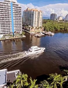 a boat in the water in front of some buildings at Luxury Waterfront Condo Hilton Hotel Amenities Beach Pool Jacuzzi Jetskis Gym in Fort Lauderdale +216 photos
