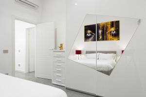 a white bedroom with a mirror on the wall at Borghese Palace Luxury Apartment in Florence