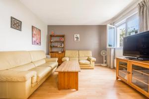 a living room with a couch and a flat screen tv at Les Marguerites - Pavillon, Wifi, TV, 2 Parkings in Chevilly-Larue