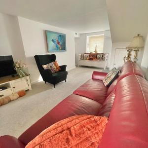 ein Wohnzimmer mit einem roten Ledersofa und einem Sessel in der Unterkunft Bear Cottage - Waterfall Country in Glyn Neath + 66 Fotos