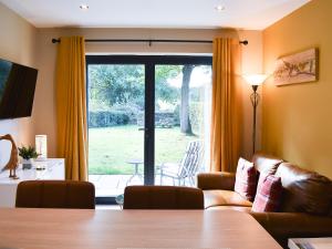 a living room with a couch and a sliding glass door at Stone Cottage in Wingerworth