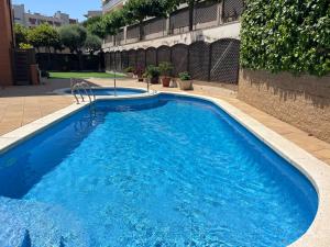 a large blue swimming pool in a building at FENALS BEACH&CHIC, Boutique Apartament, free parking, full equipped near the beach in Lloret de Mar