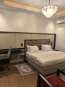 Tnmax Luxury Home Abuja في Garki: غرفة نوم بسرير وكرسي وثريا
