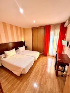 a hotel room with two beds and a desk at Hotel Fernando IV in Martos