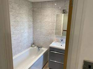 a bathroom with a bath tub and a sink at Elegant and Spacious 4 Bedroom Property with Driveway Parking in Sutton +16 photos