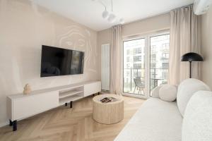 a living room with a white couch and a tv at Beige Apartment in Poznań with Parking and Air Conditioned Living Room by Noclegi Renters in Winiary +12 photos