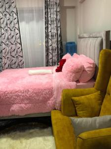 a bedroom with a pink bed and a chair at Akb Home Nyayo Studio in Nairobi