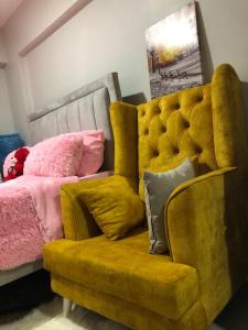 a yellow couch with pillows next to a bed at Akb Home Nyayo Studio in Nairobi +35 photos